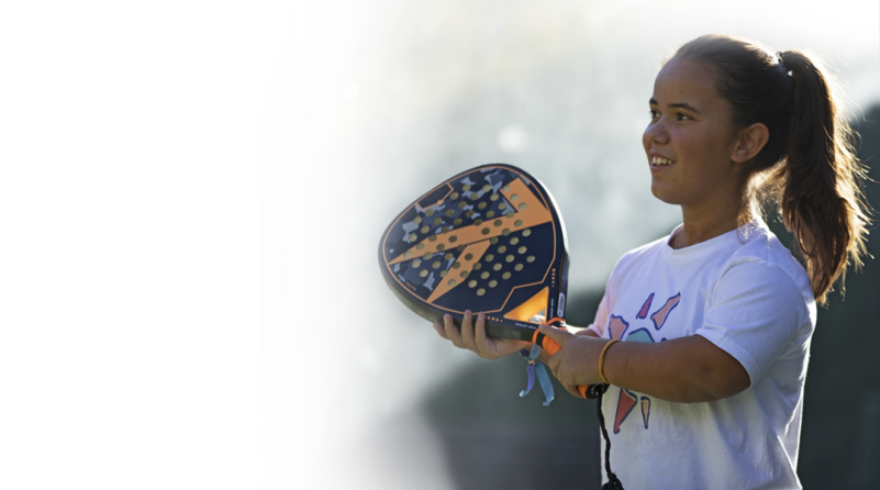 Ein junges Mädchen mit Achondroplasie hält einen Tennisschläger.