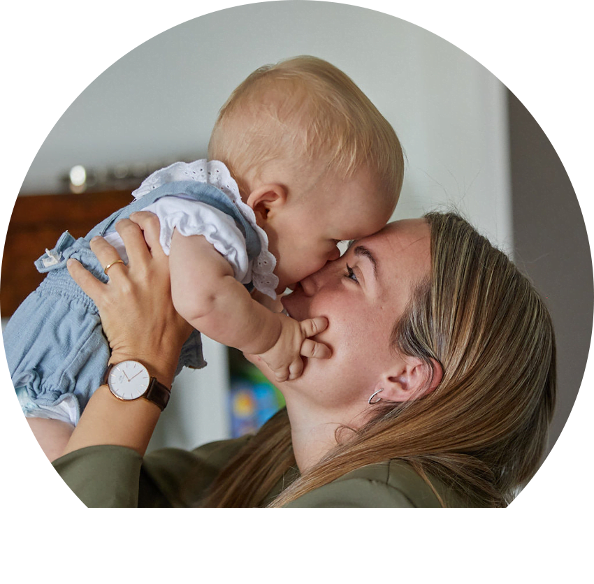 a woman holds up a baby girl with Achondroplasia face to face