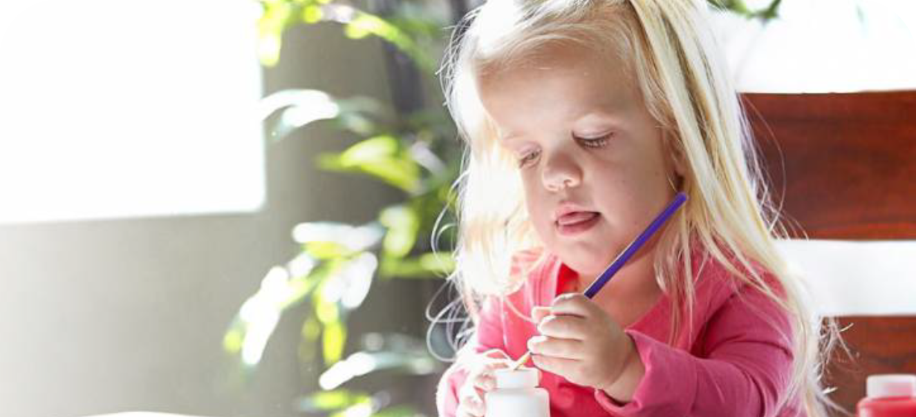 a young girl with Achondroplasia playing with a paint brush