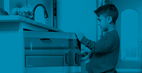 a boy with dwarfism standing at an accessible kitchen counter