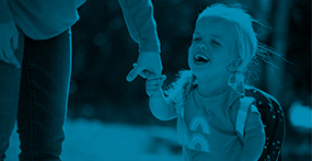 A girl with Dwarfism wearing a backpack and holding a womans hand